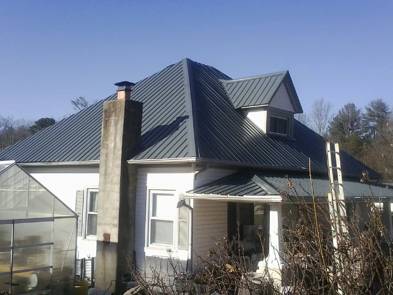 Dark blue standing seam metal roof on a white farmhouse with dormer — Slate & Tile Roof Repair by Roofing Brothers in Hay