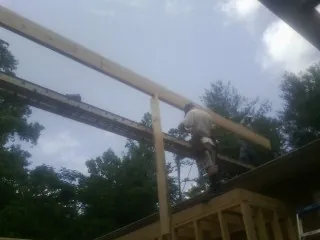 Carpenter setting a ridge beam over a new addition frame — Ice Dam Removal by Roofing Brothers in Hay