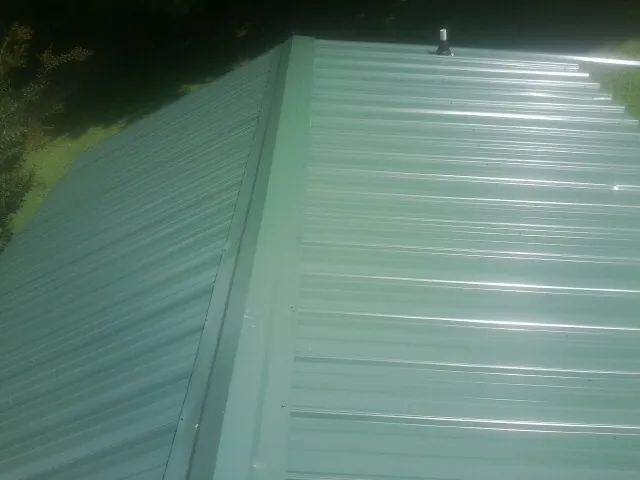 New green metal panels meeting at the ridge of a roof — Flat Roof Repair work by our crew in Hay
