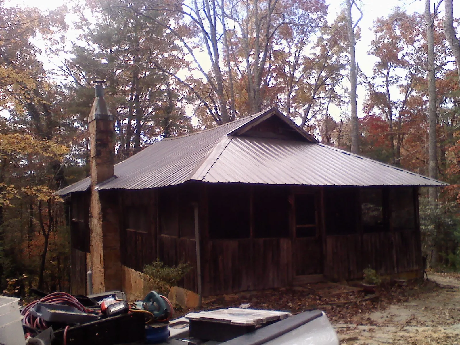 Brown metal hip roof on an old cabin with a stone chimney in Hay