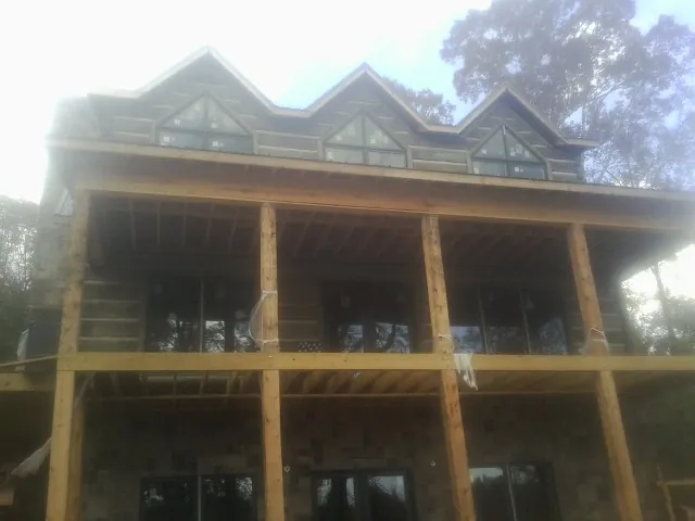 Dormers and porch framing on a large log home under construction — Roof Coating work by our crew in Hay