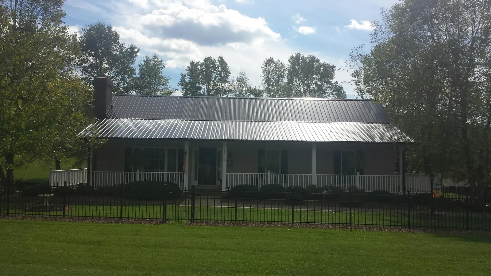 Gray metal roof on a brick ranch with a full width front porch — Gutter Guard Installation work by our crew in Hay