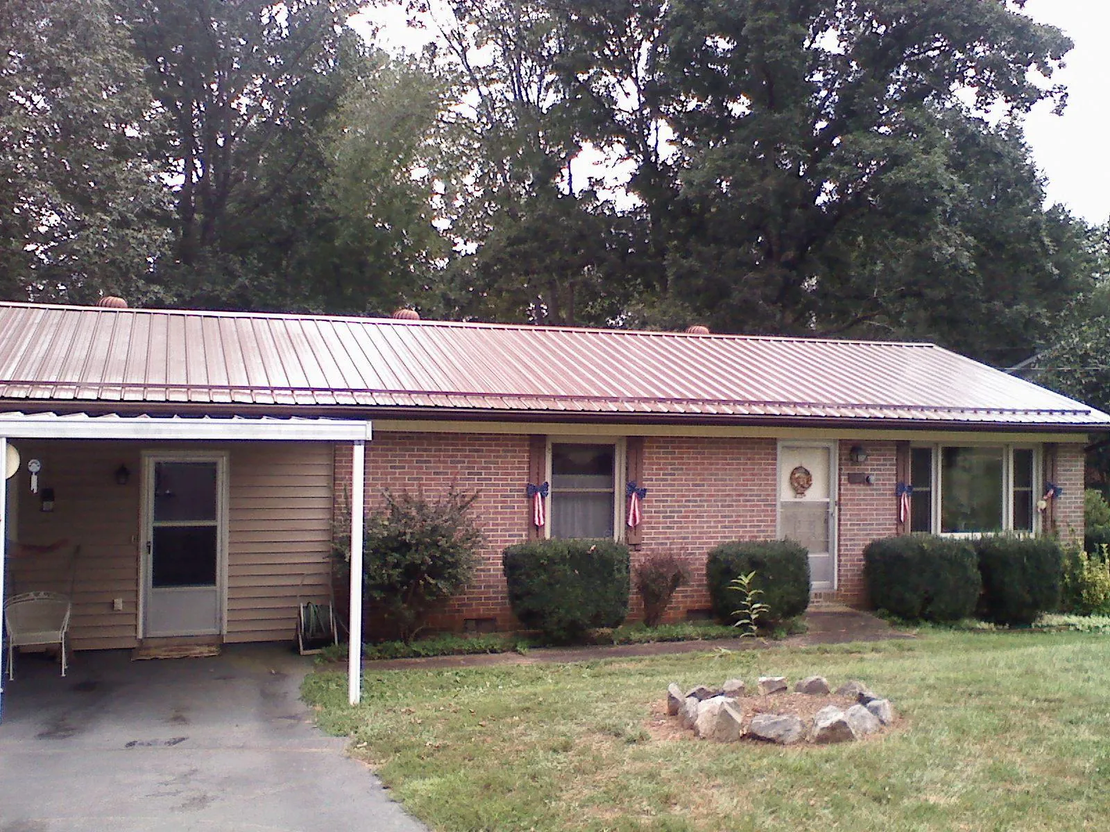 Bronze metal roof and carport on a brick ranch home — Roof Repair work by our crew in Hay