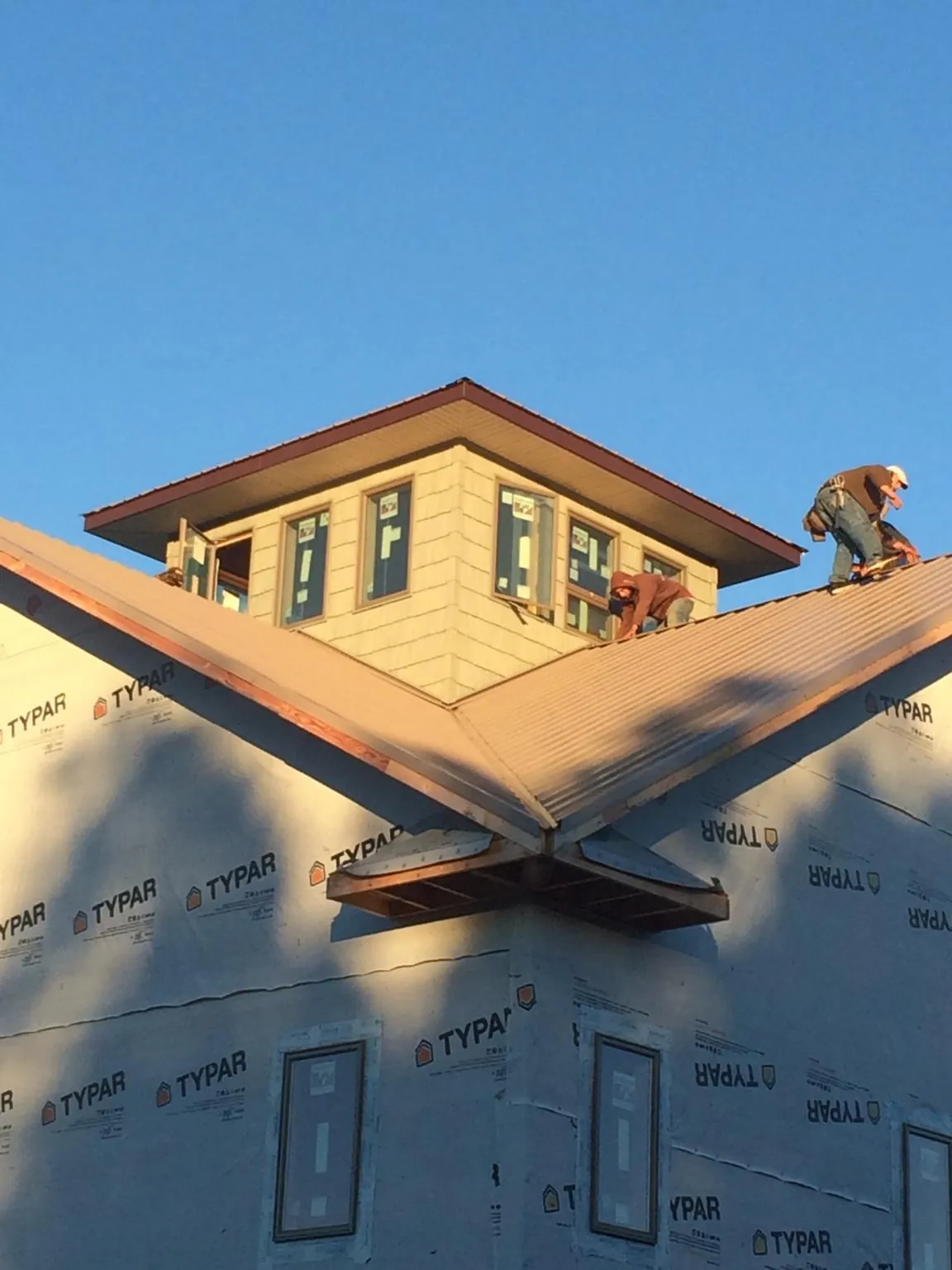 Roofers working around a rooftop cupola on a new metal roof at sunset — Roof Waterproofing in Hay by Roofing Brothers